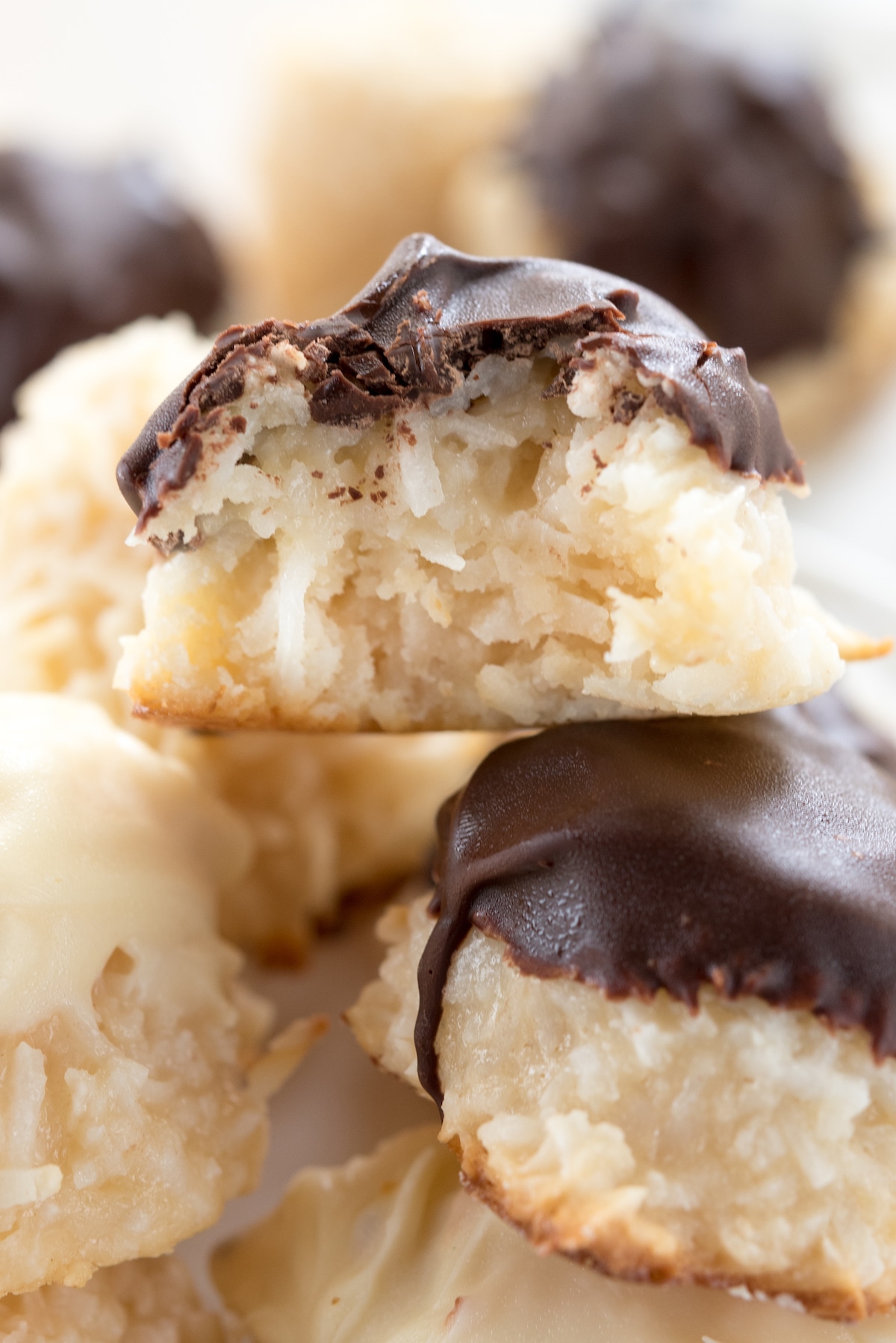 pile of chocolate dipped macaroons with bite missing.