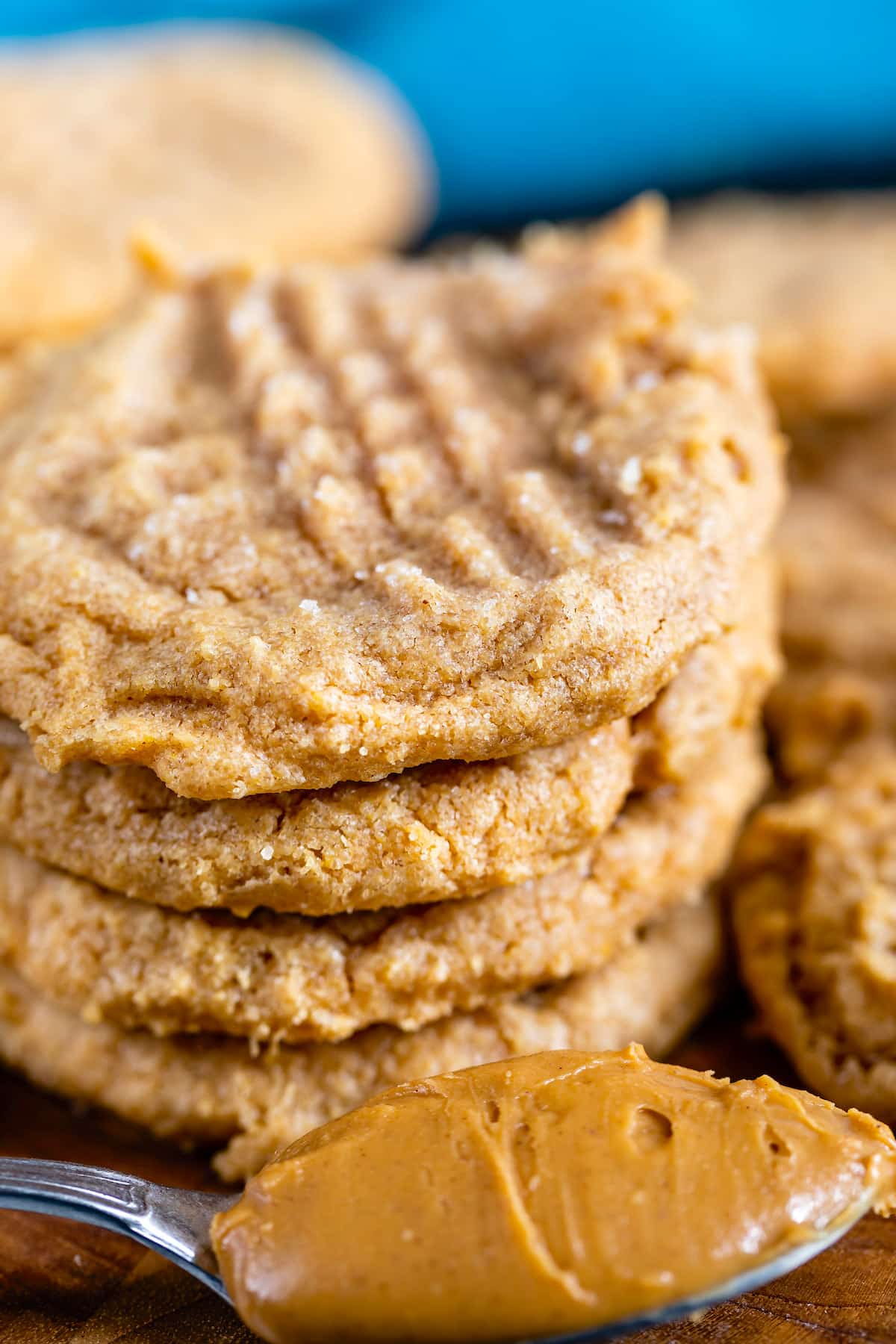 stack of 4 cookies with peanut butter spoon in front.