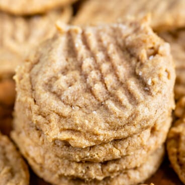 stack of 4 cookies with peanut butter spoon in front.