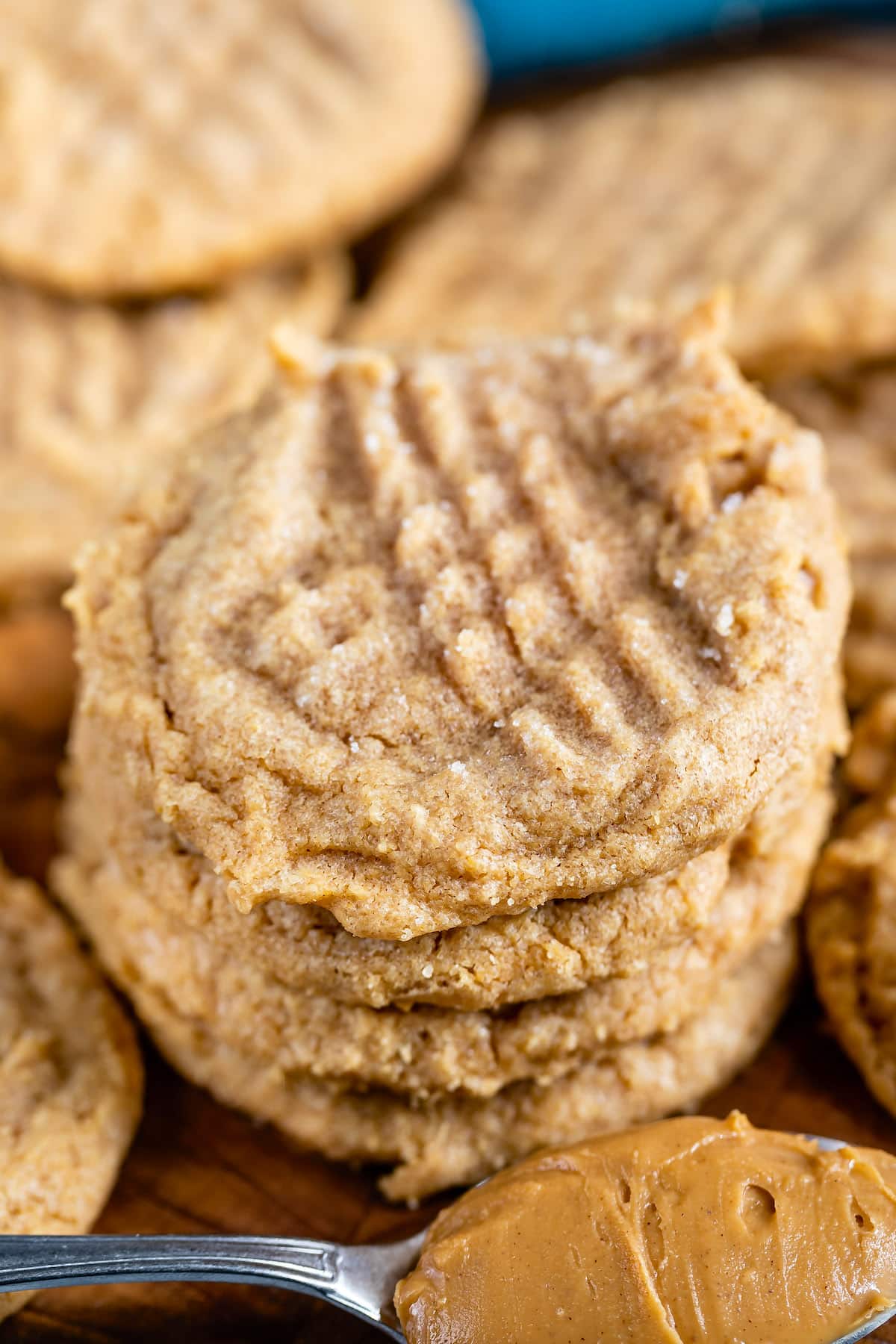 stack of 4 cookies with peanut butter spoon in front.