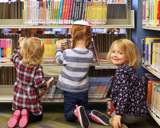 three children kneeling on floor of library