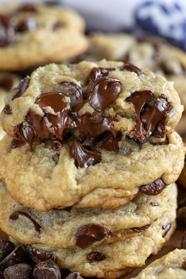 stack of chocolate chip cookies with one half of cookie on top with gooey chocolate chips