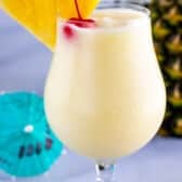 One pina colada with cherry and pineapple in top of glass