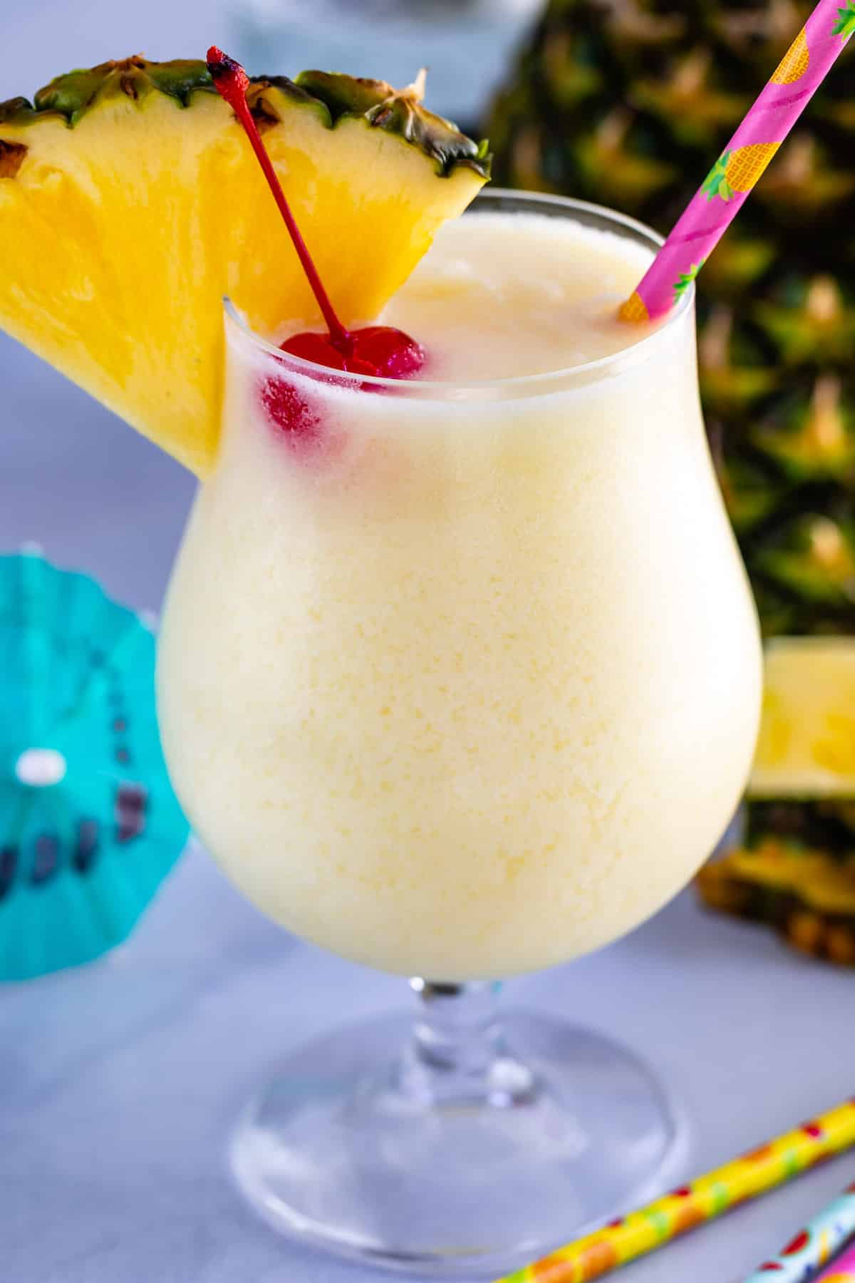 One pina colada with cherry and pineapple in top of glass