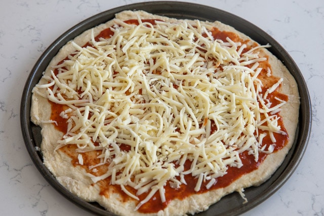 Homemade pizza and crust on pizza pan before cooking