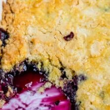 overhead shot of blueberry dump cake recipe in pan with slice missing and words on photo