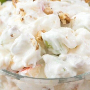 Close up shot of cheesecake apple salad in a clear bowl with ingredients at the bottom and recipe title at top of photo
