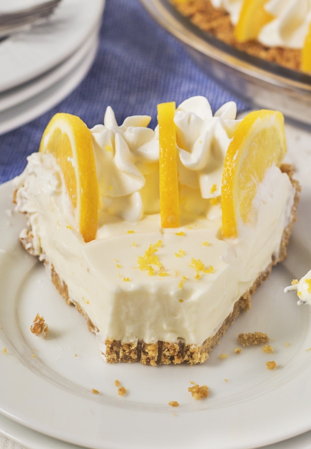 Slice of no bake lemon pie with one bite missing on a white plate