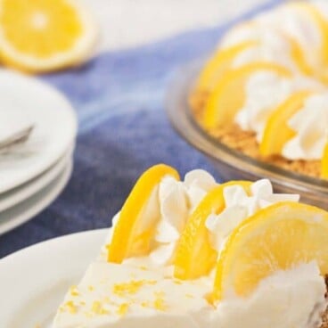 No bake lemon pie slice on white plate with fork and recipe title on top of photo in blue and yellow text