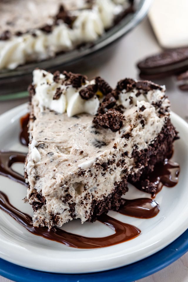 slice of oreo cheesecake on white plate with hot fudge