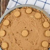 Overhead shot of nutella peanut butter pie on a wood table with blue and white checkered napkin with recipe title at top of photo