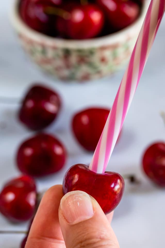 Closeup shot of using a straw to pit a cherry