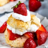 Biscuit strawberry shortcake on white plate with lots of berries and whipped cream