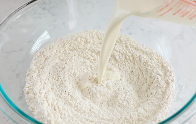 pouring heavy cream into bowl with flour