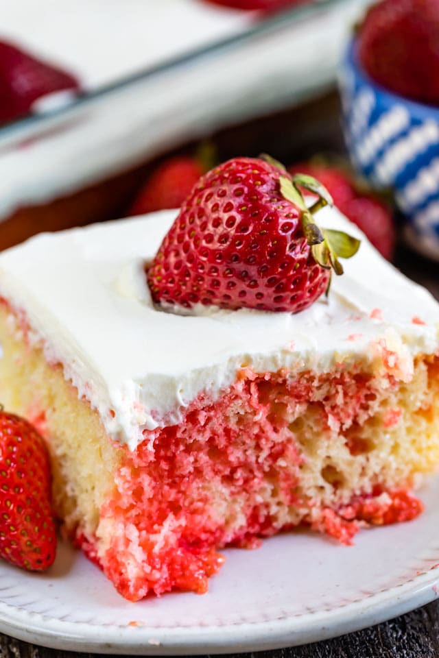 Close up of strawberry jello poke cake with a strawberry on top