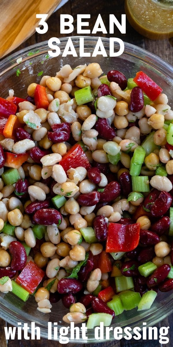 Overhead shot of three bean salad in glass mixing bowl with recipe title on top of image