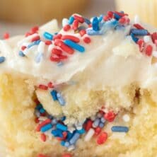 Fireworks surprise cupcake cut in half to show red white and blue sprinkle surprise in middle with recipe title on top of image