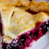 Slice of cherry pie on a white plate with recipe title on top of photo