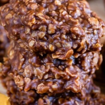 Stack of no bake cookies on wood cutting board with recipe title on top of image
