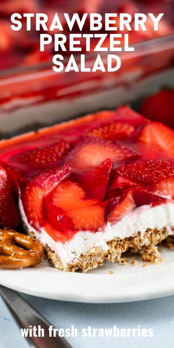 One square of strawberry pretzel salad on a white plate with recipe title in text on top of image