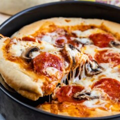 One slice of deep dish pizza being taken out of pan