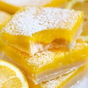 Stack of the best lemon bars with powdered sugar on top and one bite missing