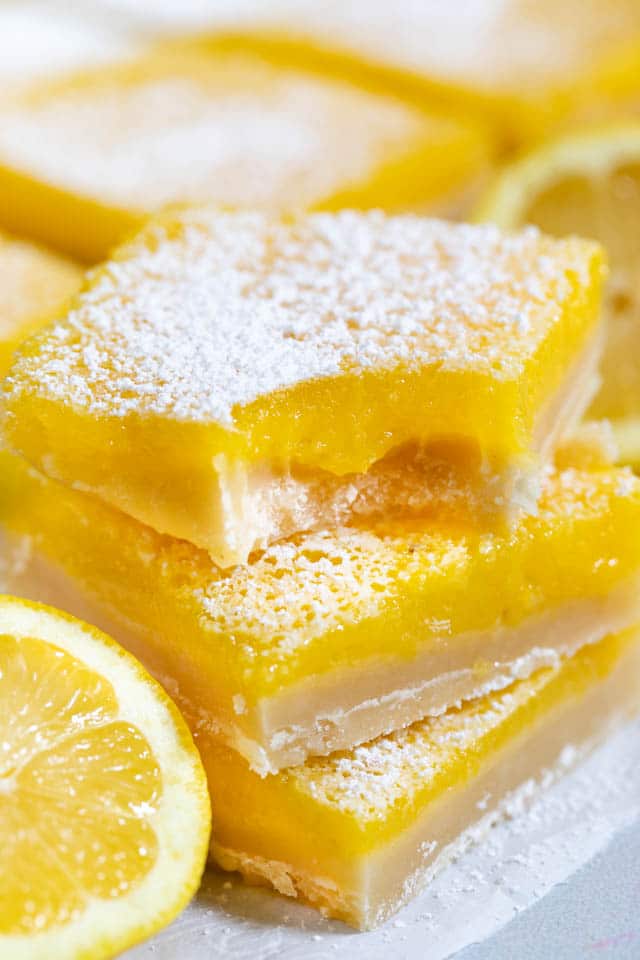 Stack of the best lemon bars with powdered sugar on top and one bite missing