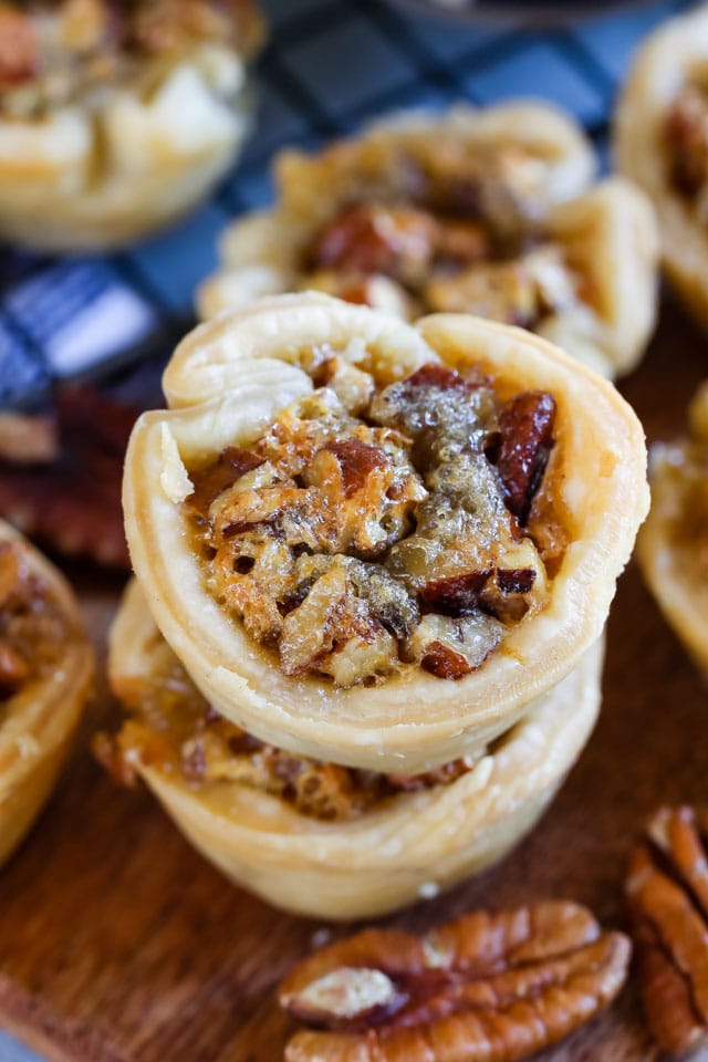 Close up shot of mini pecan pies stacked on top of eachother on cutting board