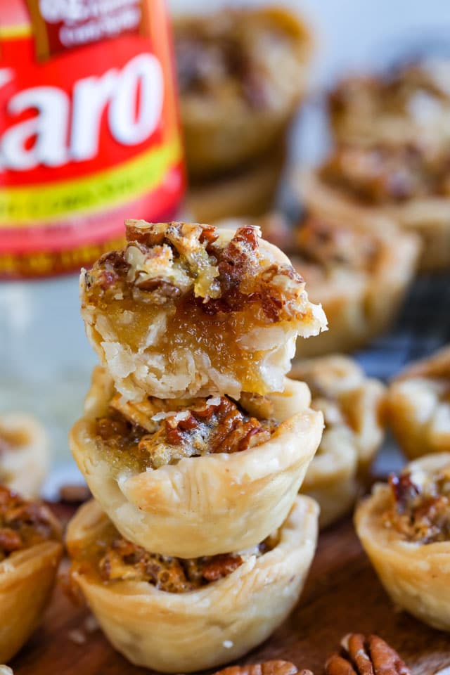 Three pecan pies stacked with top one cut in half to show filling