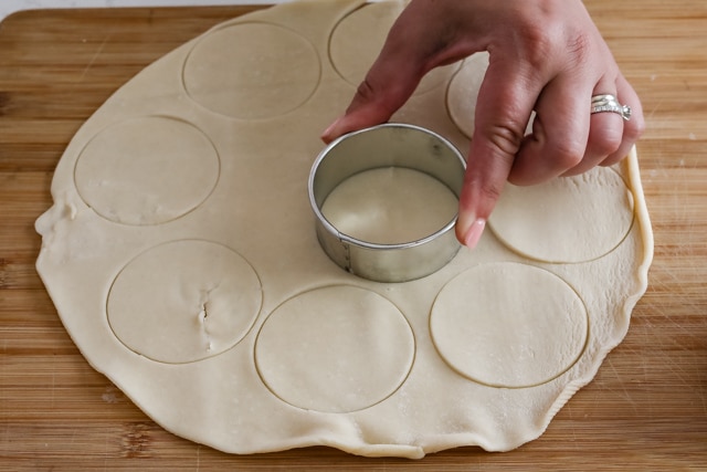 Circle cookie cutter cutting the crust on a wood cutting board