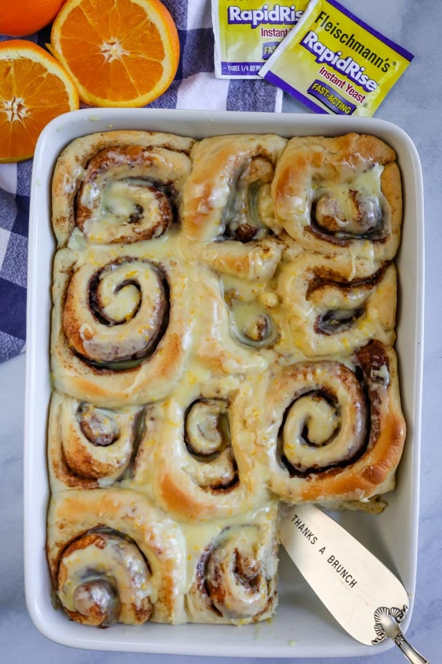 Overhead shot of orange sweet rolls in a baking dish with one cut out of the corner