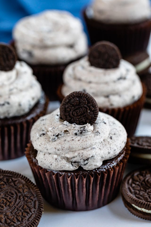 Group of oreo cupcakes on table with mini oreos on top of icing