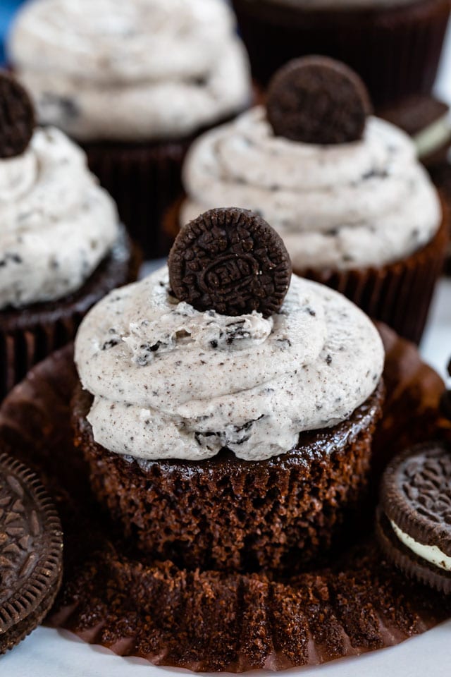 Close up of unwrapped oreo cupcake with buttercream icing and mini oreo on top