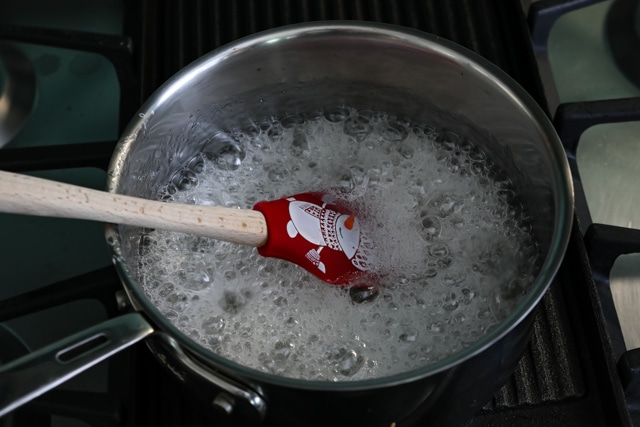 Corn syrup boiling in pot on stove with red holiday spatula