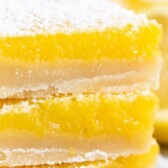 Close up photo of stack of three lemon bars on a paper towel with recipe title on top