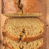 Overhead shot of biscoff banana bread loaf half sliced on wood cutting board with recipe title on top