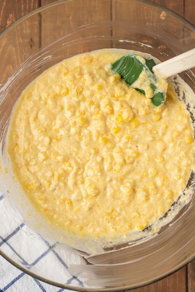 Wet ingredients of corn casserole being mixed in a glass mixing bowl