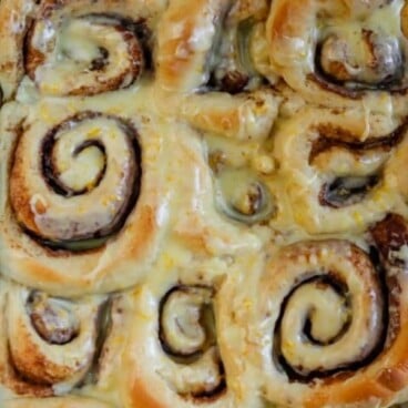 Overhead shot of orange sweet rolls in a baking dish with one cut out of the corner and recipe title on top