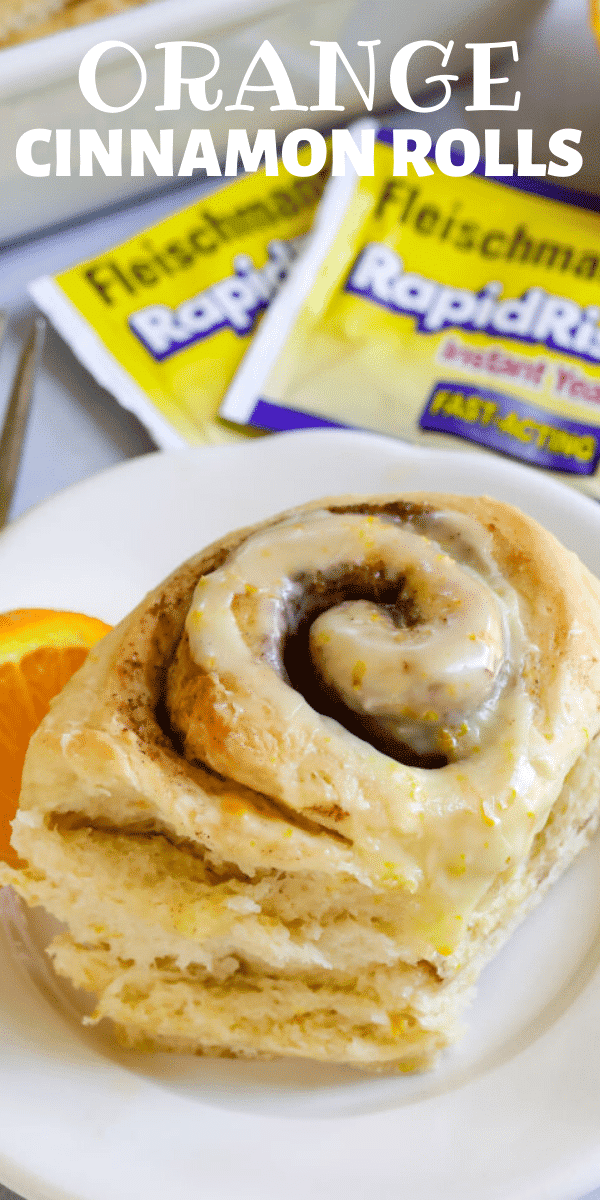 Close up photo of one orange sweet roll on a white plate with yeast packets in background with recipe title on top