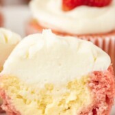 Close up of strawberry cheesecake cupcake cut in half to show filling with recipe title on top