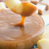 hand dipping apple in caramel