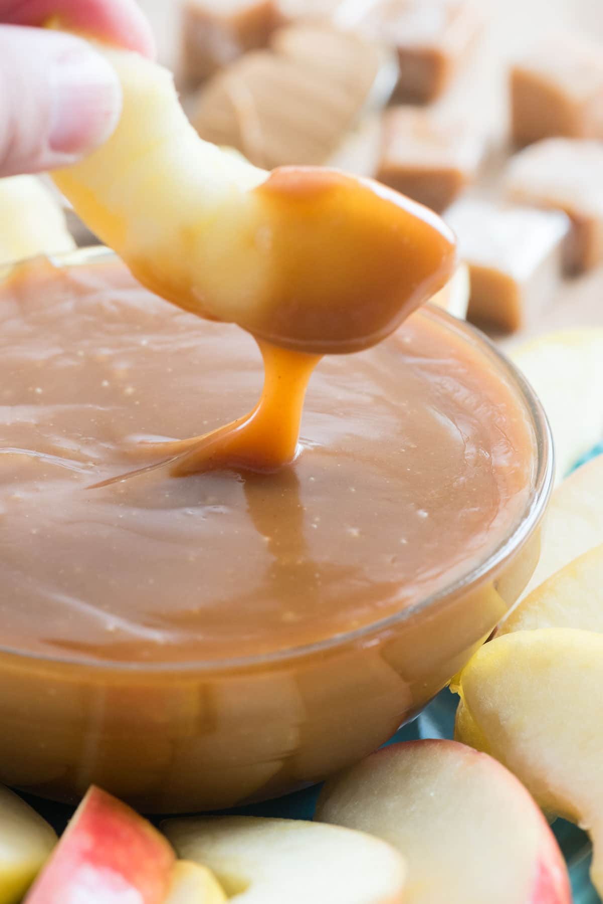 hand dipping apple in caramel