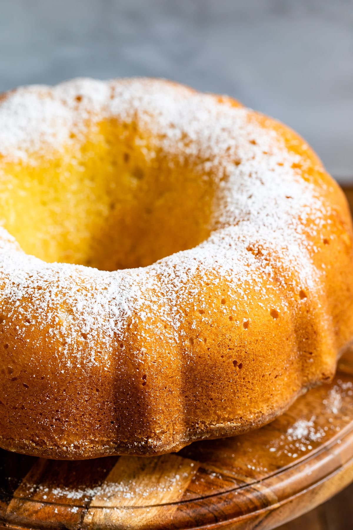 pound cake on wood stand dusted with powdered sugar