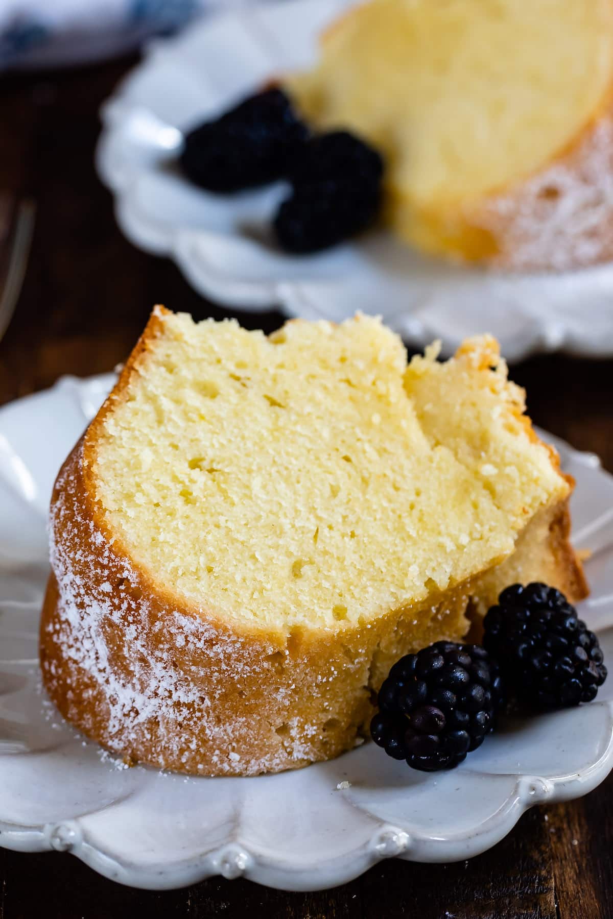 slice of pound cake on white plate with blackberries