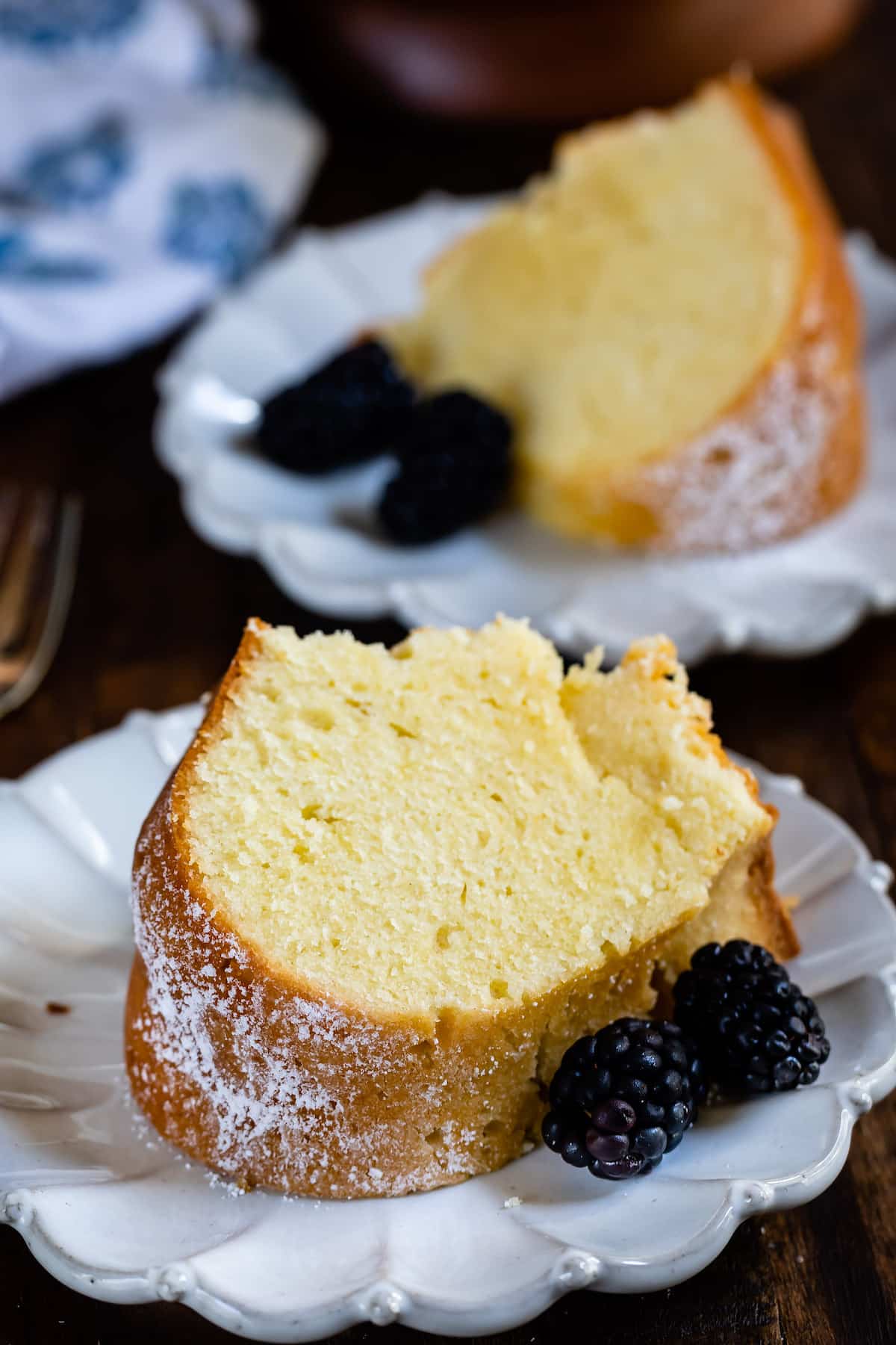 slice of pound cake on white plate with blackberries