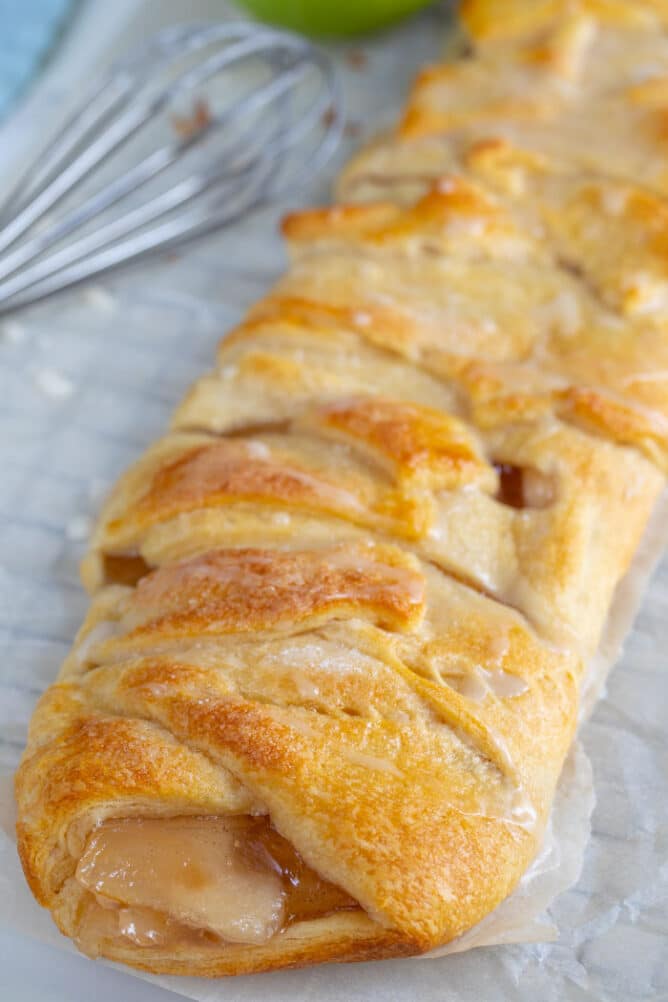 Easy apple strudel braid on parchment paper with whisk in background
