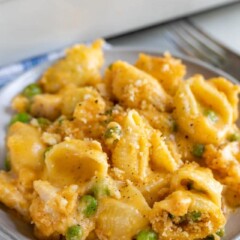 Cheesy chicken casserole on a grey dish with rest of casserole in background