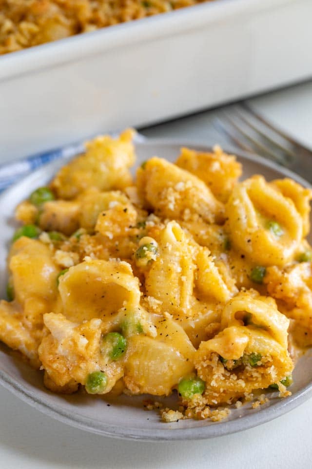 Cheesy chicken casserole on a grey dish with rest of casserole in background