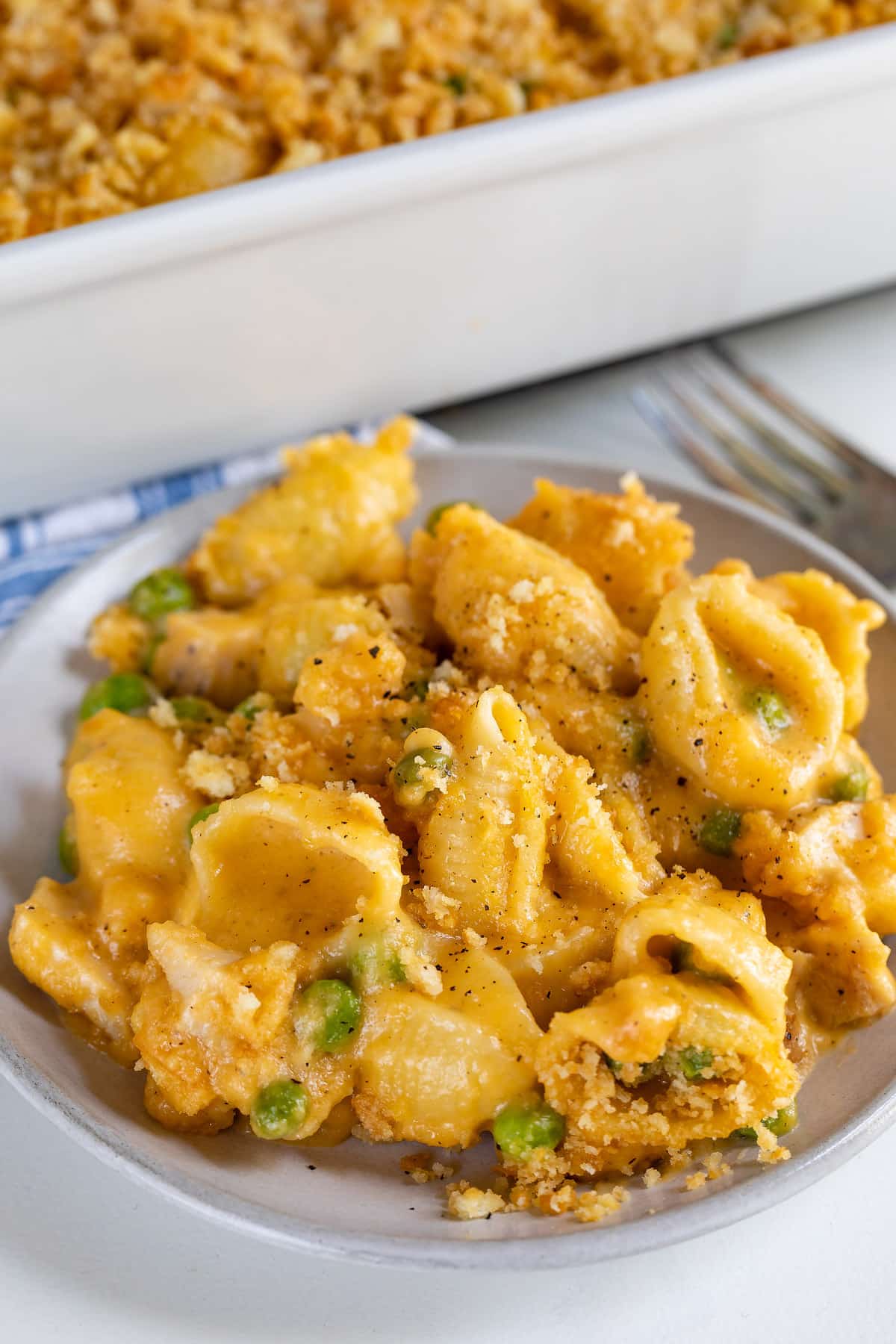 Cheesy chicken casserole on a grey dish with rest of casserole in background