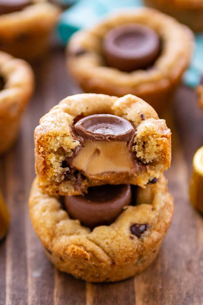 Close up of chocolate chip cookie cups stacked on top of eachother with top cut in half to show rolo filling